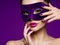 Portrait of a beautiful  woman with purple nails and violet theatre mask on face