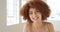 Portrait of a beautiful woman with a red afro standing in a bright room with copyspace. Closeup face of an edgy female