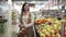 Portrait of a beautiful woman shopper with a basket for products in her hands who chooses fresh fruits and vegetables in