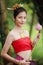 Portrait of Beautiful woman in traditional Thai red dress holding lotus in her hands and looks at the camera in the nature black