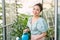 Portrait of beautiful woman watering green plants on the balcony, small cozy garden in apartment