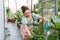 Portrait of beautiful woman watering green plants on the balcony, small cozy garden in apartment