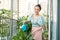 Portrait of beautiful woman watering green plants on the balcony  small cozy garden in apartment