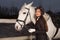 Portrait of beautiful woman with white horse outdoors, evening walk