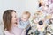 Portrait of beautiful young adult caucasian woman wiht cute adorable little blond toddler boy enjoy trimming christmas tree in