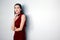 Portrait of  beautiful  young asian woman in a red dress posing with hand on chin and looking away on white background