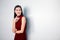 Portrait of  beautiful  young asian woman in a red dress posing with hand on chin and smiling , looking away on white background