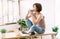 Portrait of beautiful young Asian woman relax sitting on office desk  enjoying her cup of coffee and thoughtfully looking out of