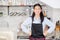 Portrait of beautiful young barista, asian woman is a employee standing in counter coffee shop