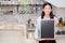 Portrait of beautiful young barista, asian woman is a employee standing holding chalkboard