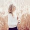 Portrait of a beautiful young blonde girl in a field in white pullover, smiling, concept beauty and health