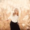 Portrait of a beautiful young blonde girl in a field in white pullover, smiling, concept of beauty and health