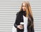 Portrait of a beautiful young blonde girl with long hair posing on a street with coffee and a backpack. Outdoor, warm color. Close