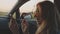 Portrait of beautiful young blonde making selfie on her phone or smartphone in front seat of the car. Pretty girl in