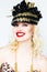 Portrait of beautiful young blonde woman in extravagant hat on white background