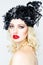 Portrait of beautiful young blonde woman in extravagant hat on white background