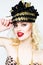 Portrait of beautiful young blonde woman in extravagant hat on white background