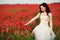 Portrait of beautiful young bride in field full of red poppies