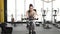 Portrait of a beautiful young brunette woman doing cardio on a exercise bike at gym. Moving away video.