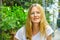 Portrait of beautiful young caucasian woman with long blond hair blue eyes sitting in European American street cafe