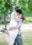 Portrait of beautiful young couple female bride and male bridegroom kissing in summer park. Man husband raised woman wife. Couple