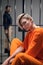 Portrait of a beautiful young criminal in a prison cell against the background of bars and guards