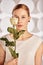 Portrait of a beautiful young disabled woman, born without an arm, holding a flower in her hands in a white dress