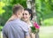 Portrait of a beautiful young female bride with small wedding pink flower roses bouquet smiling, gently hugging bridegroom neck an