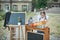 Portrait of a beautiful young first-grader sitting at a desk on the background autumn park. Farewell Bell. day of knowledge. begin