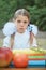 Portrait of a beautiful young first-grader sitting at a desk on the background autumn park. Farewell Bell. day of knowledge. begin