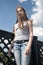 Portrait of beautiful young girl on the bridge blue sky background with blowing hair in wind