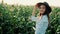 Portrait of beautiful young girl in hat standing at a corn field smiling and looking at camera in the Sunset light