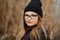 Portrait of a beautiful young girl near the lake in the reeds in a dark leather jacket and glasses