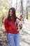 Portrait of beautiful young girl in red shirt hold small pet dog toy terrier in bow during walk in sunny forest