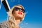 Portrait of a beautiful young girl in sunglasses looking afar, against the blue sky