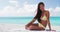 Portrait of beautiful young multiracial Woman sitting on white sand beach in front of the sea