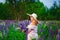 Portrait of a beautiful young plump woman in a straw hat and a bouquet of lupines on the field. He stands on a blooming meadow