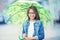 Portrait of beautiful young pre-teen girl with umbrella under rain