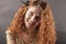 Portrait of a beautiful young red curly girl with bright makeup in a fashionable gold dress