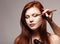 Portrait of beautiful young redheaded woman with esthetician making makeup
