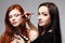 Portrait of beautiful young redheaded woman with esthetician making makeup