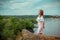 Portrait of beautiful young smiling woman standing on the cliff above the river with her eyes closed