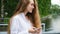 Portrait of a beautiful young successful woman with a phone. European girl with long hair uses a smartphone and prints a