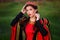 Portrait of a beautiful, young woman in a black and red medieval dress with a crown on her head. Princess walk in the green field.