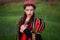 Portrait of a beautiful, young woman in a black and red medieval dress with a crown on her head. Princess walk in the green field.