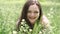 Portrait of a beautiful young woman blowing on the ripened dandelion in the park