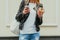 Portrait of a beautiful young woman eating a donut, looks at her smart phone on the street European city. Body part. Outdoor.