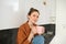 Portrait of beautiful young woman enjoying her morning cup of aromatic coffee, drinking tea while sitting in kitchen and