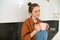 Portrait of beautiful young woman enjoying her morning cup of aromatic coffee, drinking tea while sitting in kitchen and