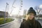 Portrait of beautiful young woman in front of London Eye, London, UK